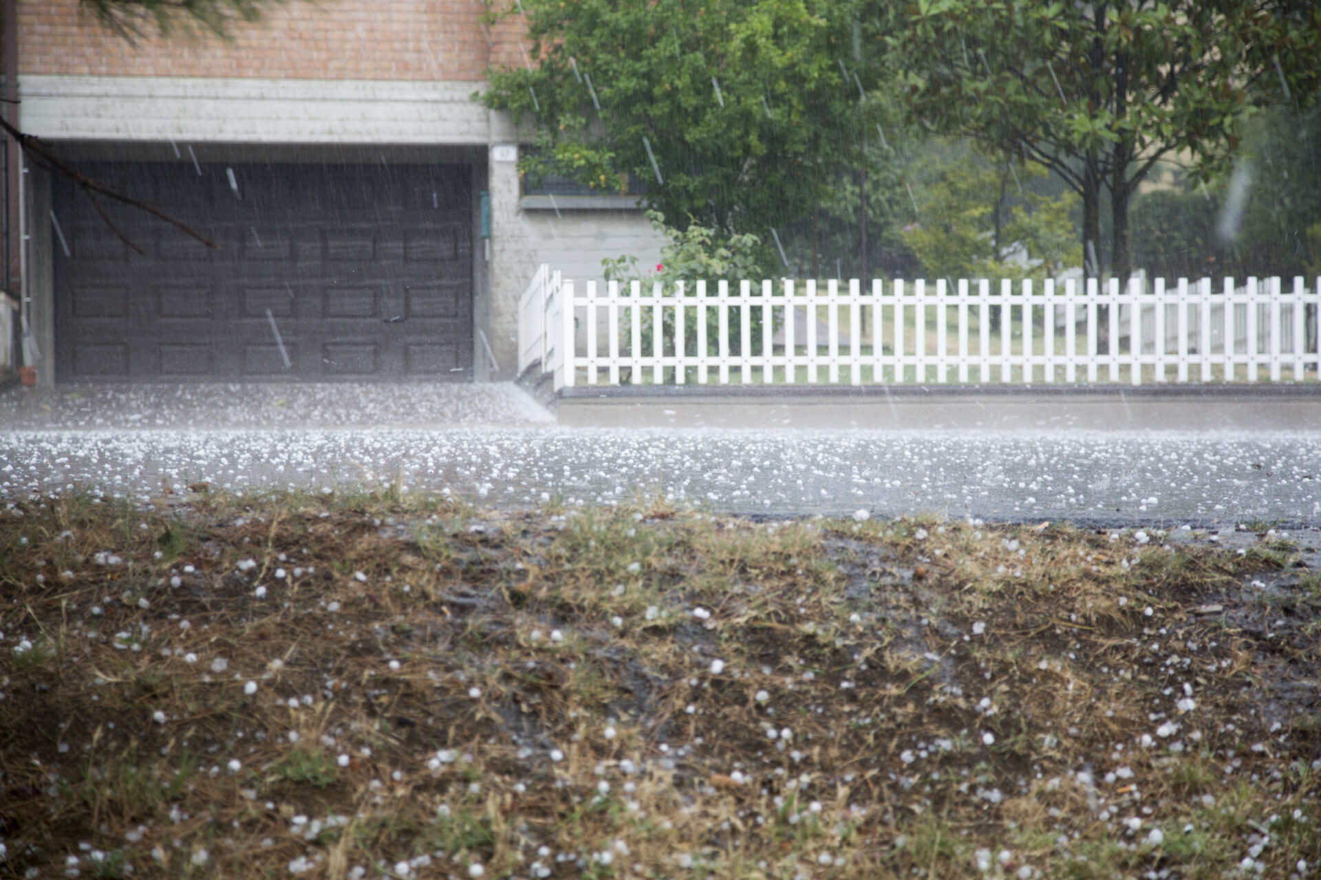 The front of a home and yard in the middle of a hail storm.