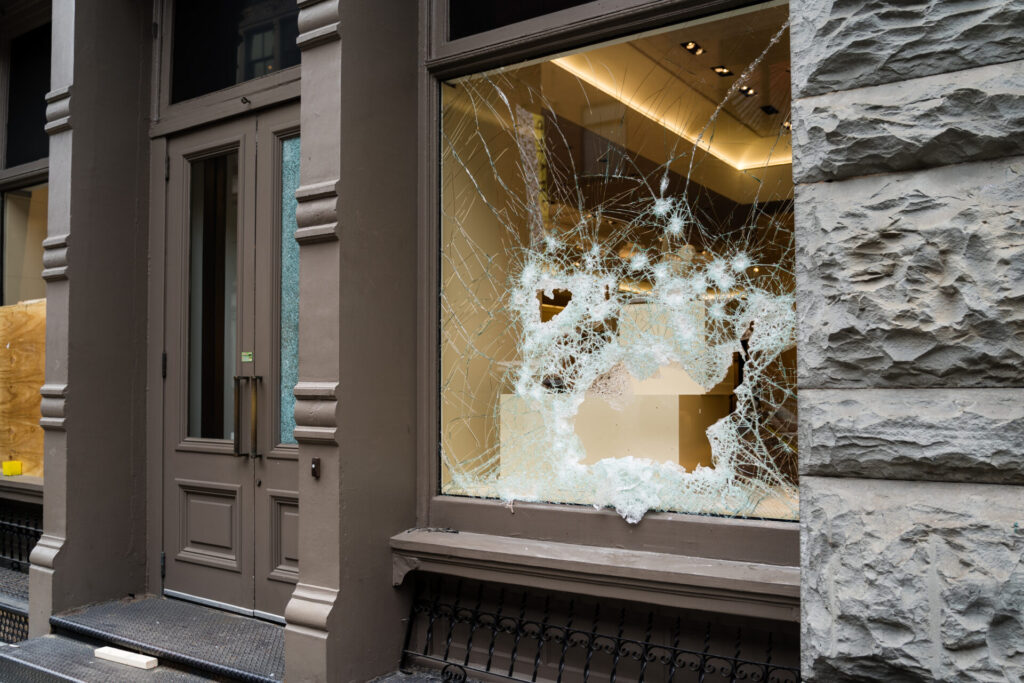 A storefront with a broken window that has been smashed by vandals 